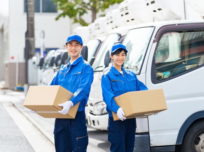 トラックの前で荷物を持つ配達員